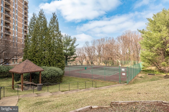 view of tennis court with a yard and fence