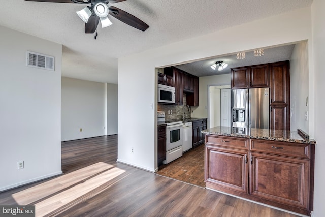 kitchen with visible vents, ceiling fan, dark wood finished floors, white appliances, and a sink