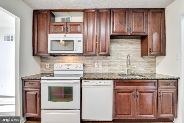 kitchen with tasteful backsplash, visible vents, dark stone counters, white appliances, and a sink