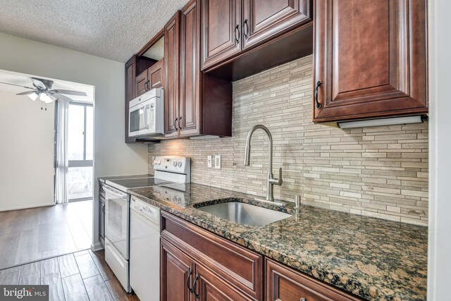 kitchen with a ceiling fan, a sink, wood finished floors, white appliances, and decorative backsplash