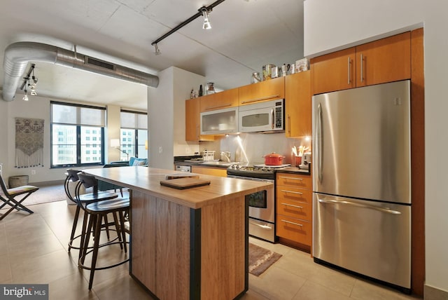 kitchen with stainless steel appliances, rail lighting, a center island, and a breakfast bar area