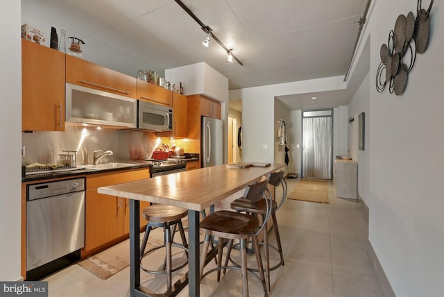 kitchen featuring stainless steel appliances, sink, decorative backsplash, and light tile patterned floors