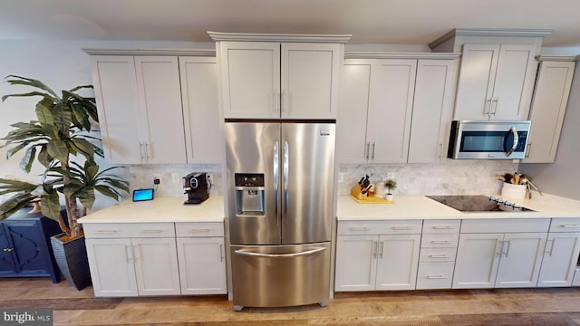 kitchen with backsplash, stainless steel appliances, and light hardwood / wood-style floors