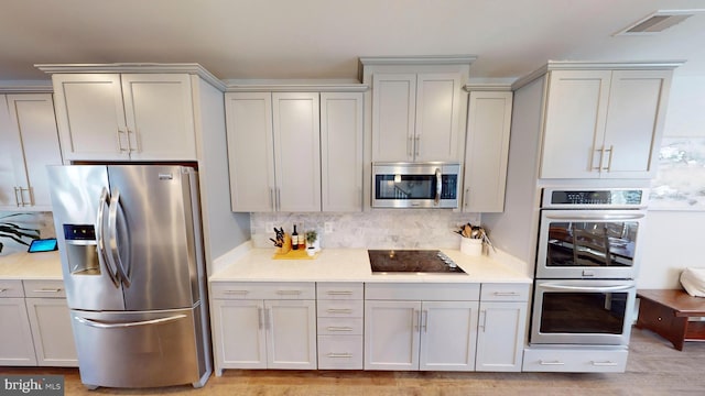 kitchen with stainless steel appliances and decorative backsplash