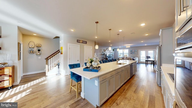 kitchen featuring a breakfast bar, decorative light fixtures, sink, light hardwood / wood-style floors, and a spacious island