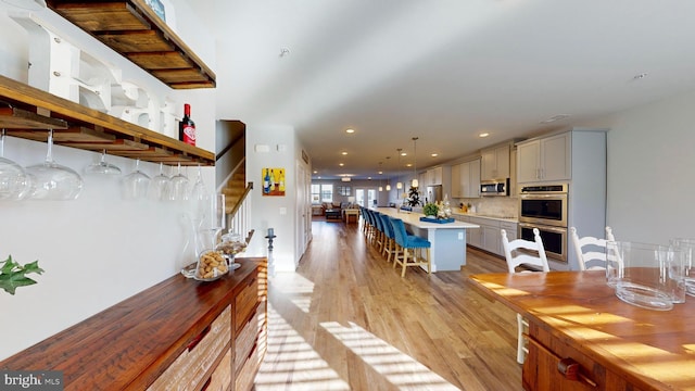 interior space with gray cabinets, a breakfast bar, hanging light fixtures, stainless steel appliances, and a center island