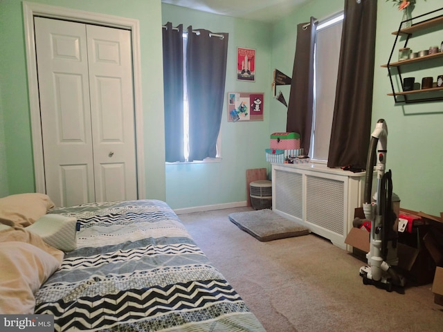 bedroom with a closet, radiator, and light carpet