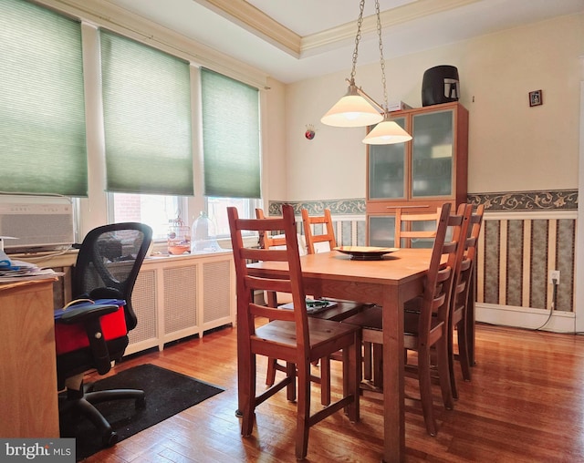 dining room with a raised ceiling, wood-type flooring, and ornamental molding