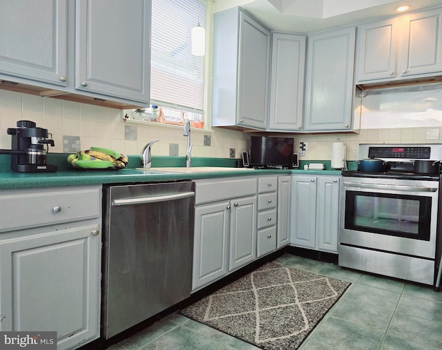 kitchen featuring tile patterned floors, sink, gray cabinetry, stainless steel appliances, and backsplash