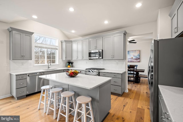 kitchen with a breakfast bar, sink, gray cabinetry, a center island, and stainless steel appliances