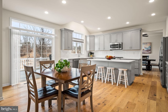 dining space featuring lofted ceiling, sink, and light hardwood / wood-style floors