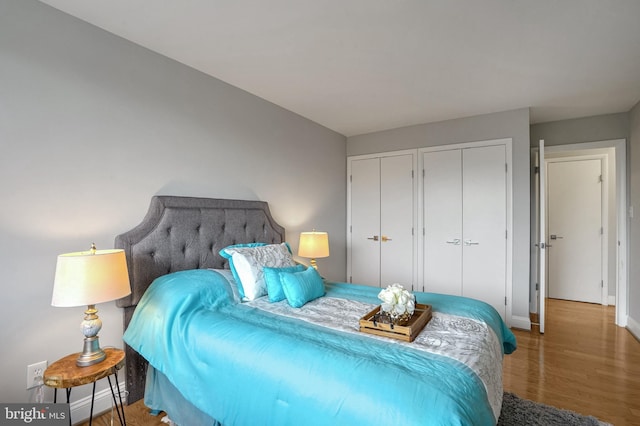 bedroom featuring hardwood / wood-style flooring and multiple closets