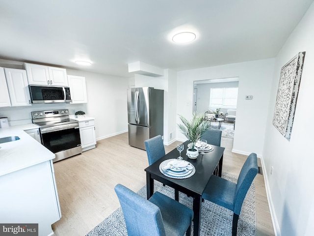 kitchen with white cabinetry, appliances with stainless steel finishes, sink, and light hardwood / wood-style flooring