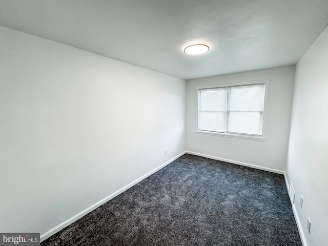 spare room with dark carpet