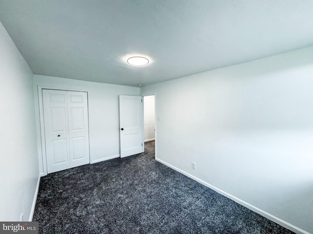 unfurnished bedroom with dark carpet and a closet