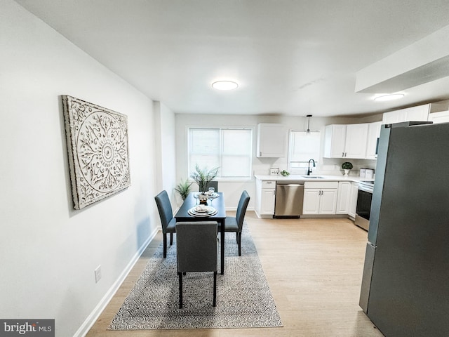 kitchen featuring stainless steel appliances, sink, white cabinets, and light hardwood / wood-style floors