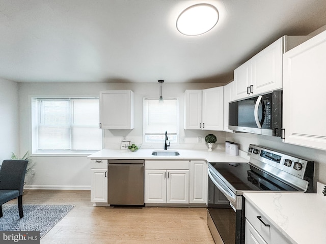 kitchen featuring stainless steel appliances, white cabinetry, sink, and pendant lighting