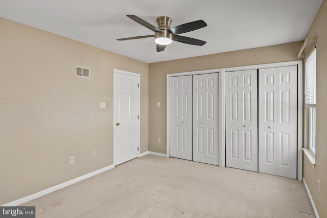 unfurnished bedroom with multiple closets, light colored carpet, and ceiling fan