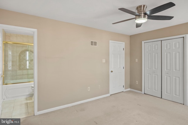 unfurnished bedroom with ceiling fan, light carpet, ensuite bath, and a closet