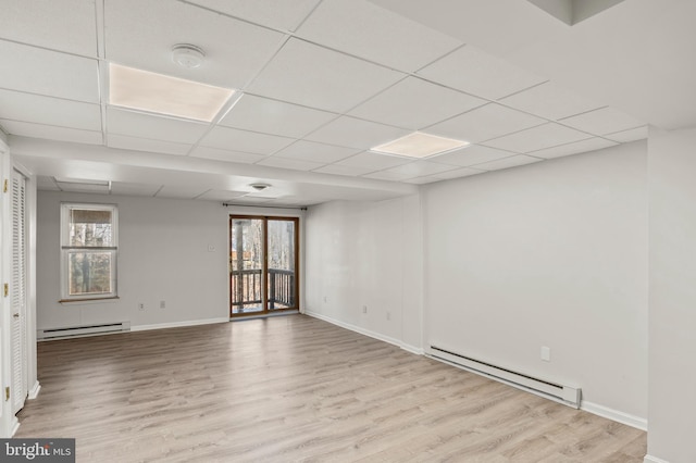 unfurnished room featuring baseboard heating, light hardwood / wood-style flooring, and a wealth of natural light