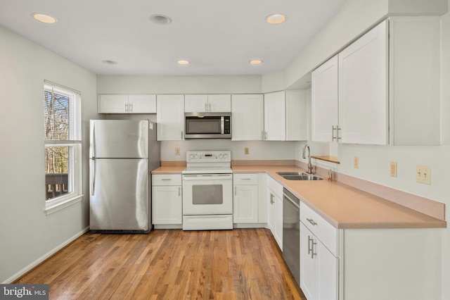 kitchen with sink, light hardwood / wood-style flooring, white cabinets, and appliances with stainless steel finishes