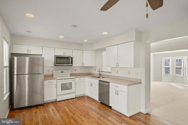 kitchen with sink, ceiling fan, appliances with stainless steel finishes, white cabinets, and light wood-type flooring