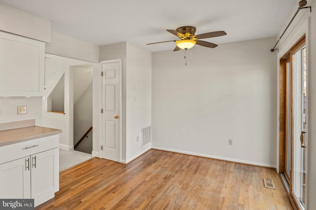 interior space with ceiling fan, white cabinets, and light wood-type flooring