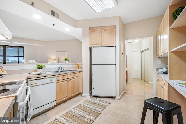 kitchen featuring white appliances, light countertops, a sink, and light brown cabinets