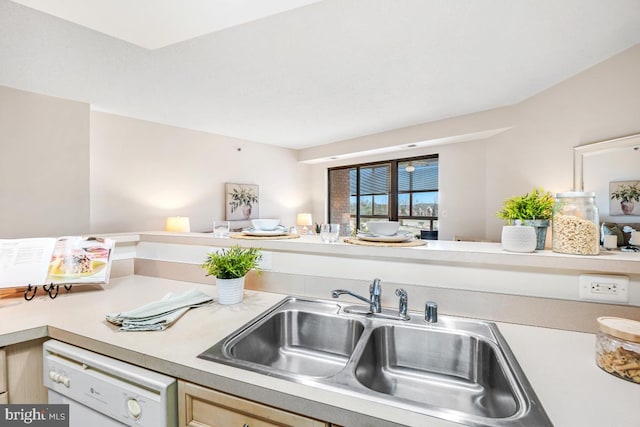 kitchen featuring white dishwasher, light countertops, a sink, and light brown cabinetry