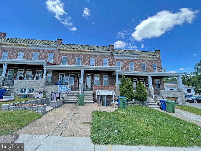 view of property with covered porch and a front lawn