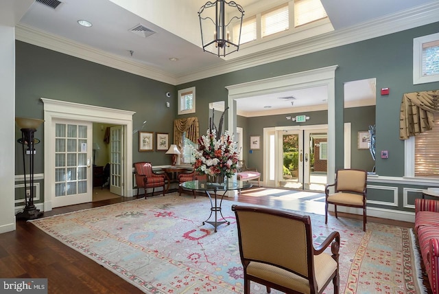 living area with visible vents, ornamental molding, french doors, an inviting chandelier, and wood finished floors