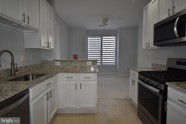 kitchen with a ceiling fan, a sink, stainless steel appliances, a peninsula, and white cabinets