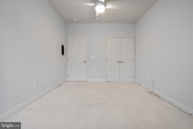 unfurnished bedroom featuring a closet, light colored carpet, baseboards, and ceiling fan