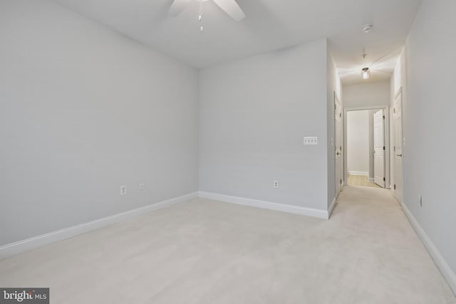 spare room with light carpet, ceiling fan, and baseboards