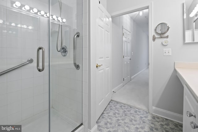 bathroom featuring baseboards, vanity, and a shower stall