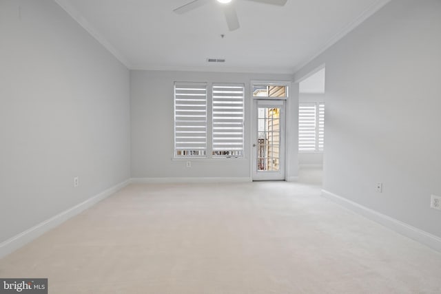 unfurnished room featuring a ceiling fan, baseboards, visible vents, ornamental molding, and light colored carpet