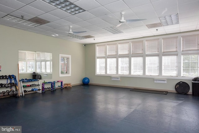 gym with a ceiling fan, a wealth of natural light, and a paneled ceiling