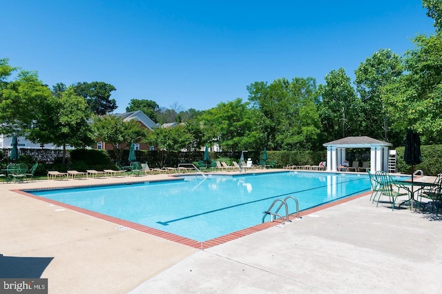 community pool with a patio and fence