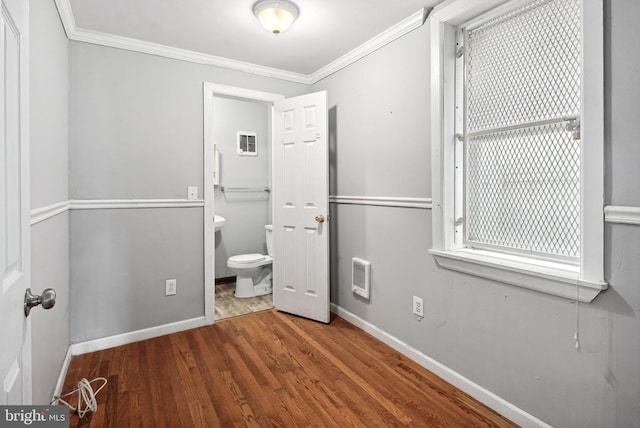 unfurnished bedroom featuring ornamental molding, wood-type flooring, ensuite bathroom, and heating unit