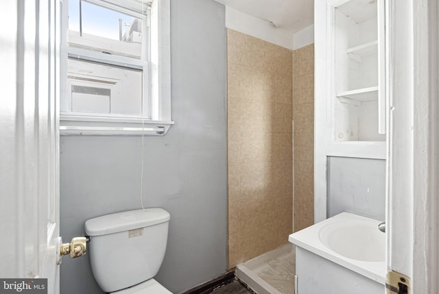 bathroom with vanity, toilet, and tiled shower