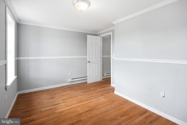 spare room with a baseboard heating unit, ornamental molding, and light hardwood / wood-style floors