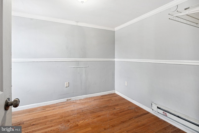 spare room featuring a baseboard heating unit, crown molding, and hardwood / wood-style floors