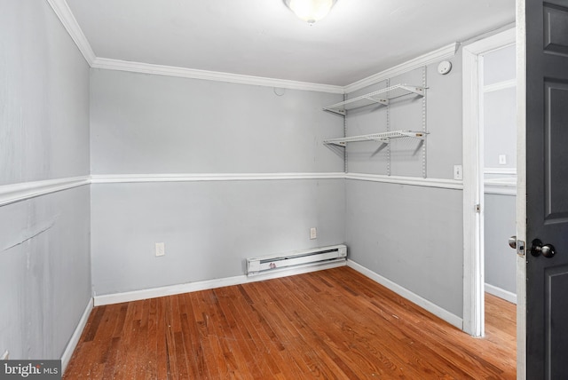 empty room featuring hardwood / wood-style flooring, ornamental molding, and baseboard heating