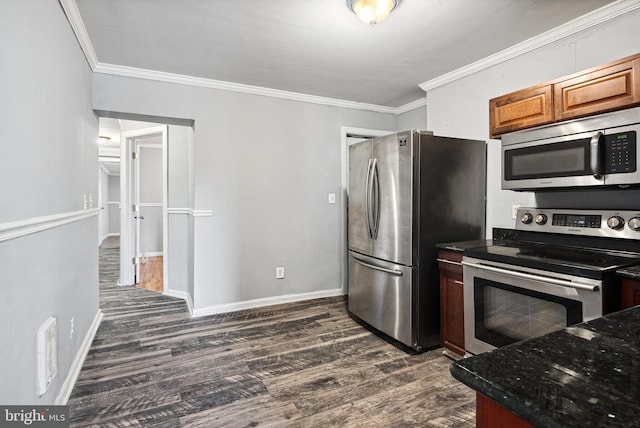 kitchen with dark wood-type flooring, ornamental molding, dark stone counters, and appliances with stainless steel finishes