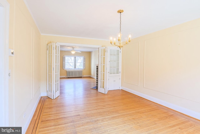 unfurnished dining area with crown molding, radiator heating unit, an inviting chandelier, and light hardwood / wood-style floors