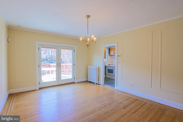 empty room with an inviting chandelier, radiator heating unit, ornamental molding, and light wood-type flooring