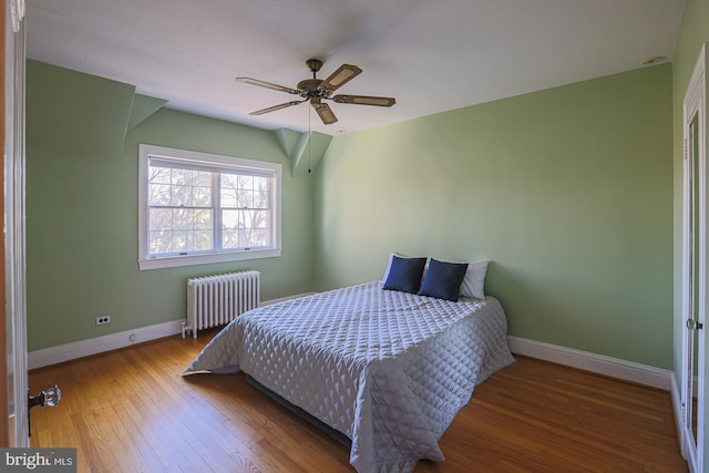 bedroom featuring hardwood / wood-style floors, radiator heating unit, and ceiling fan