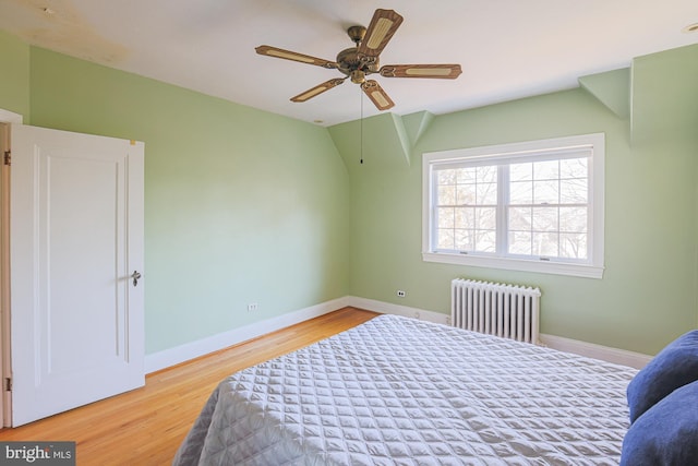 bedroom with vaulted ceiling, radiator, hardwood / wood-style floors, and ceiling fan