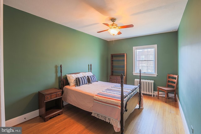 bedroom featuring radiator, hardwood / wood-style floors, and ceiling fan