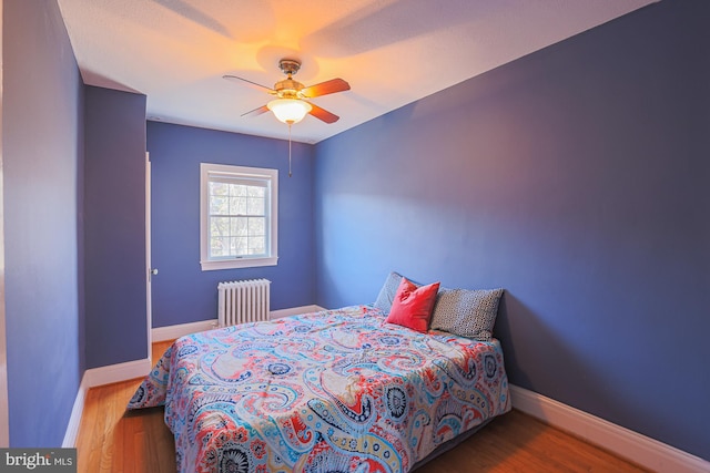 bedroom featuring ceiling fan, radiator, and hardwood / wood-style floors